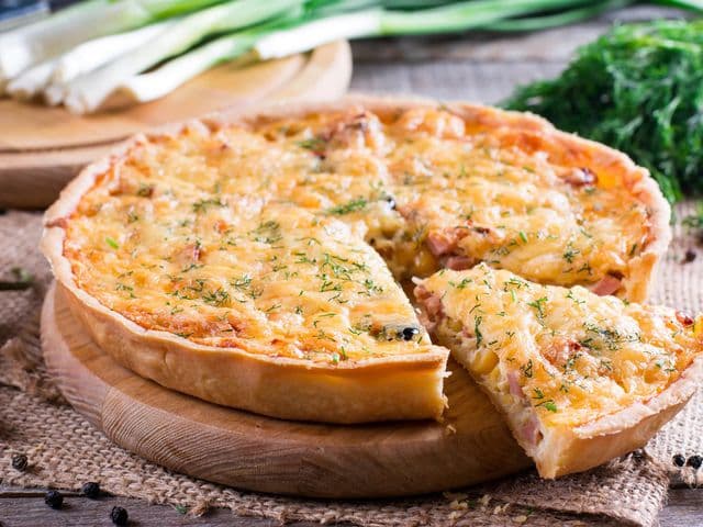 A piece of French quiche Lorraine on wooden background
