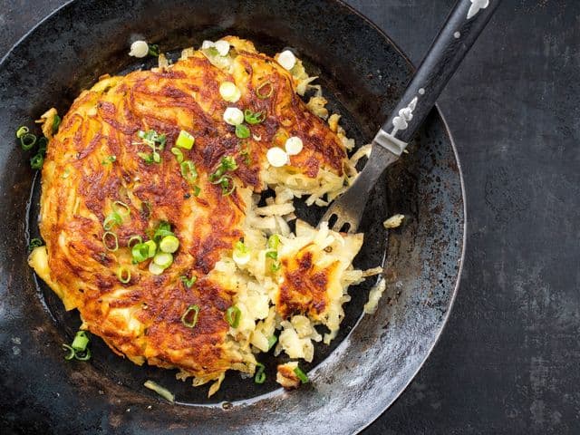 Traditional Swiss rosti as side dish with leek as top view in a
