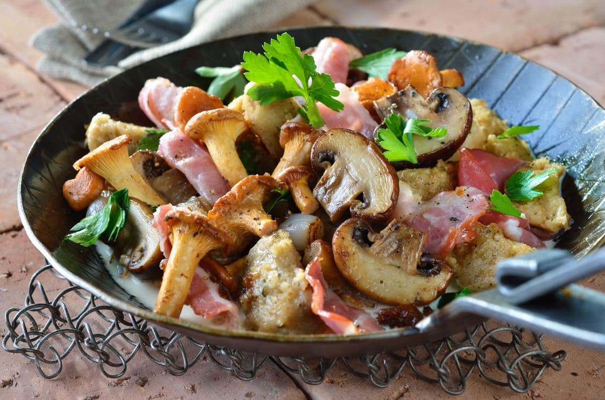 Gusseisenpfanne mit Champignons, Pfifferlingen, Speck und frischer Petersilie.