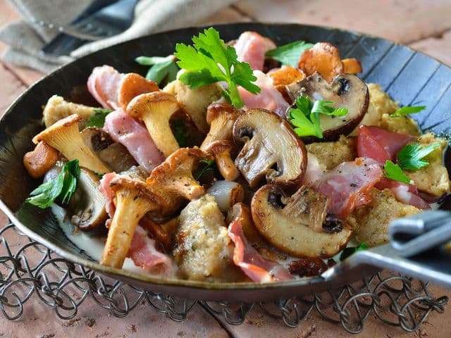 Gusseisenpfanne mit Champignons, Pfifferlingen, Speck und frischer Petersilie.