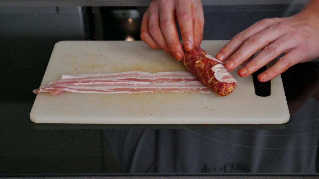Wenn ihr die fertig geformten Sticks leicht schräg an den Bacon ansetzt, kommt ihr mit einer Scheibe Bacon komplett drum.