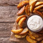 knusprige Kartoffel Wedges mit Sour Cream Dip auf Holzbrett